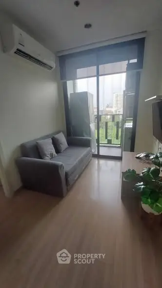 Cozy living room with sofa, TV, and balcony view in modern apartment.