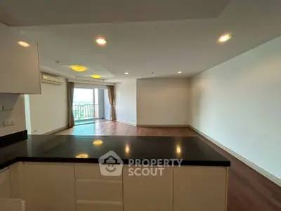 Spacious open-plan living room with hardwood floors and balcony view.