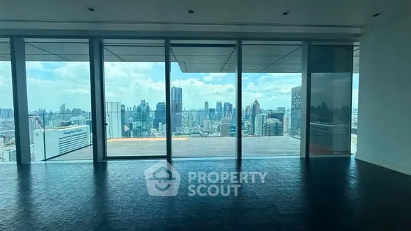 Spacious modern living room with floor-to-ceiling windows offering stunning city skyline views.