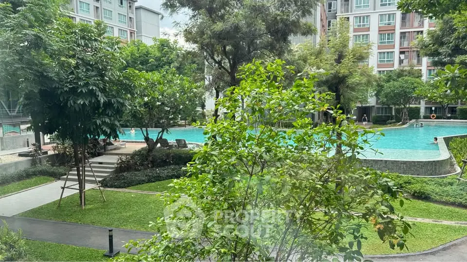 Luxurious residential pool surrounded by lush greenery and modern apartment buildings.