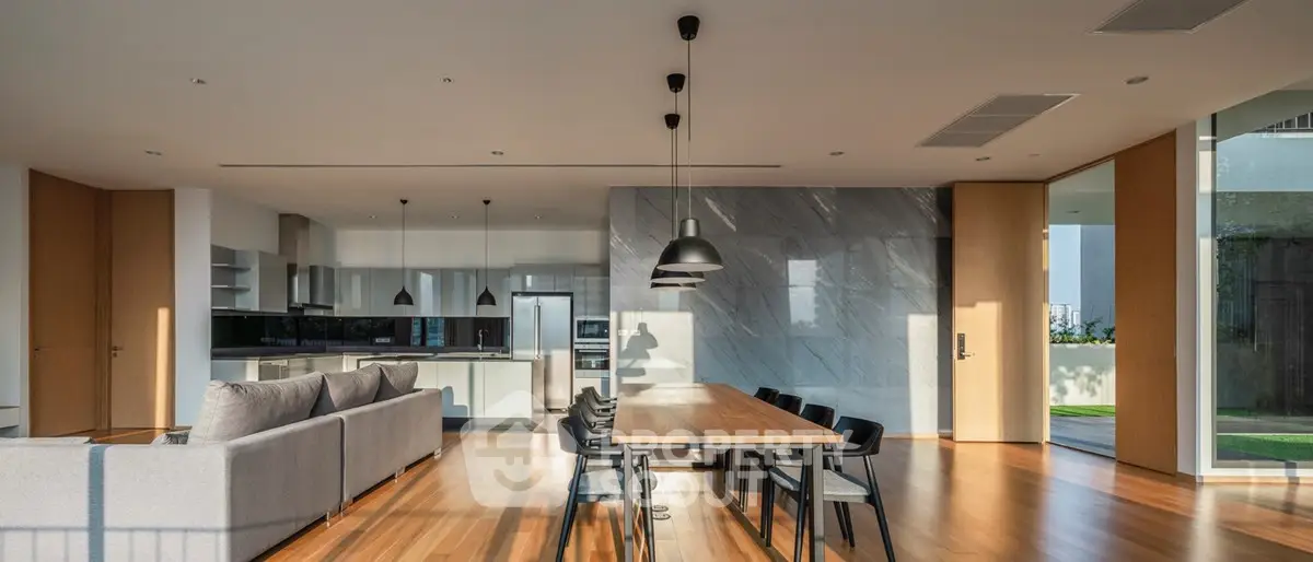 Spacious modern living room with open kitchen and dining area, featuring sleek design and abundant natural light.