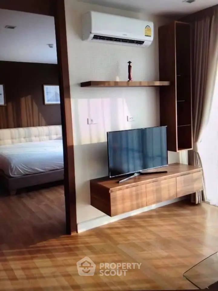 Modern living room with sleek TV unit and cozy bedroom view, featuring wooden flooring and elegant decor.