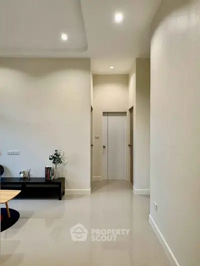 Modern living room with sleek design and neutral tones, featuring recessed lighting and minimalist decor.