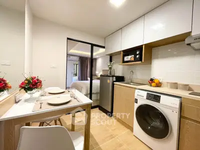Modern compact kitchen with washing machine and dining area in cozy apartment