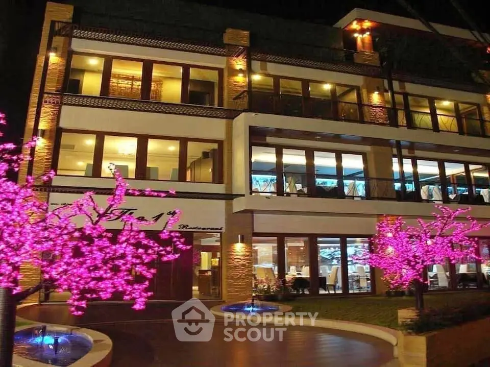 Stunning modern building with vibrant pink illuminated trees at night, perfect for upscale dining or events.