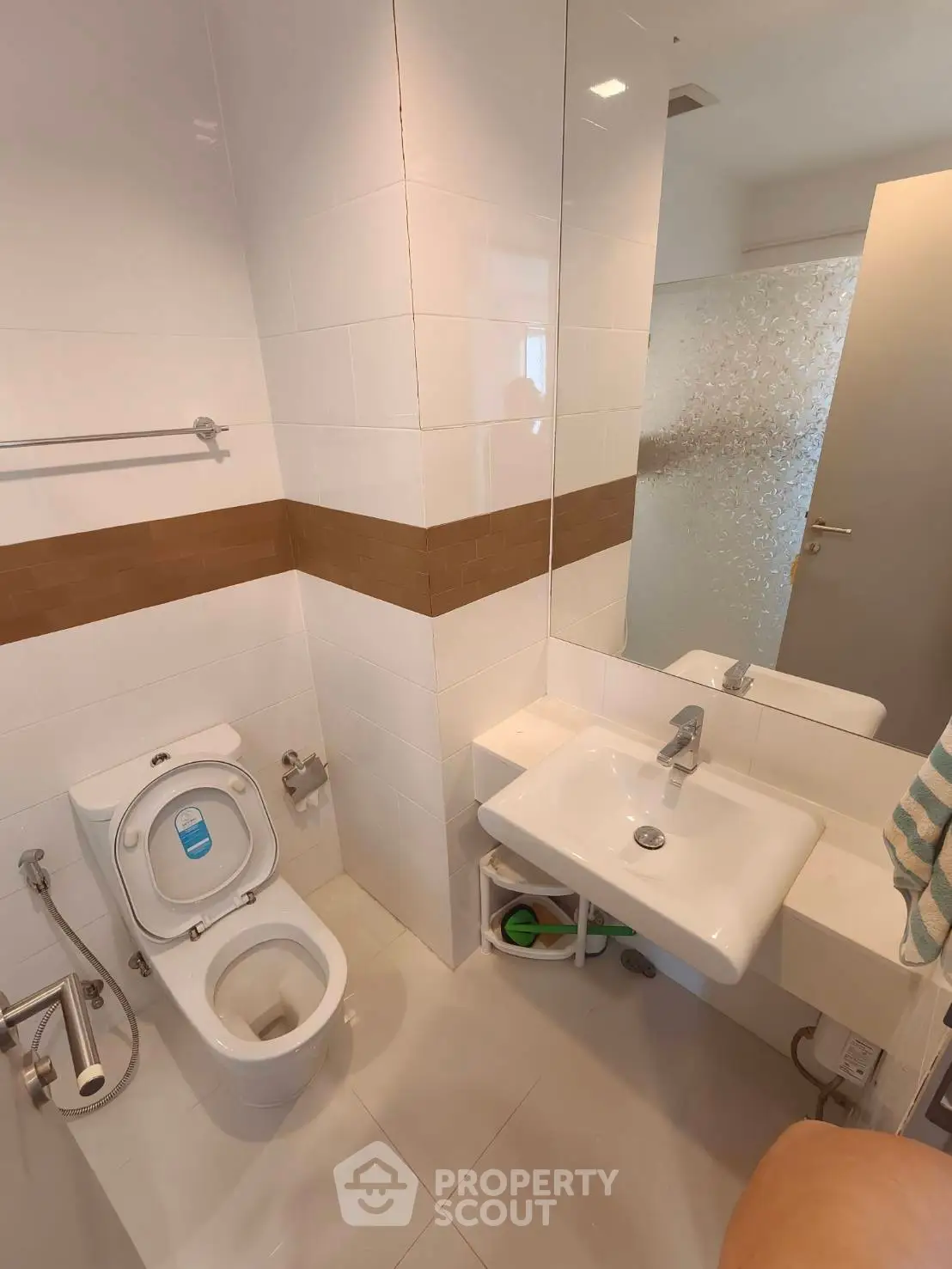 Modern bathroom with sleek white fixtures and stylish brown accent tiles.