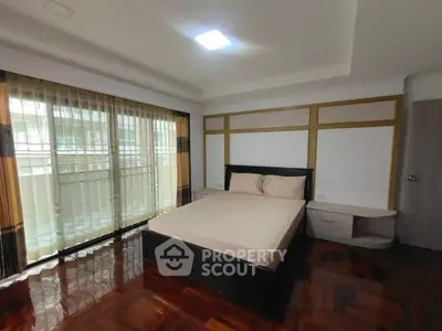 Spacious bedroom with large windows and elegant wooden flooring