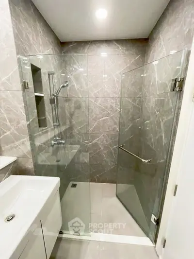 Modern bathroom with glass shower enclosure and sleek marble tiles