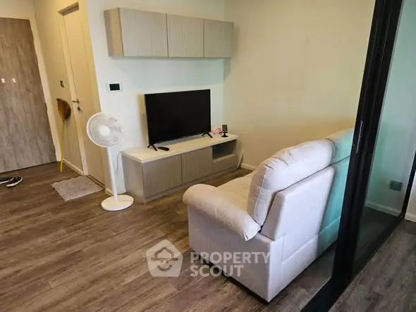 Cozy living room with modern decor and wooden flooring, featuring a comfortable sofa and sleek TV setup.