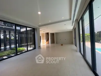 Spacious modern living room with large windows and pool view, perfect for luxury living.