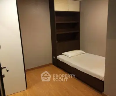 Cozy minimalist bedroom with wooden flooring and built-in shelving.