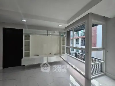 Modern living room with sleek built-in storage and large windows offering natural light.