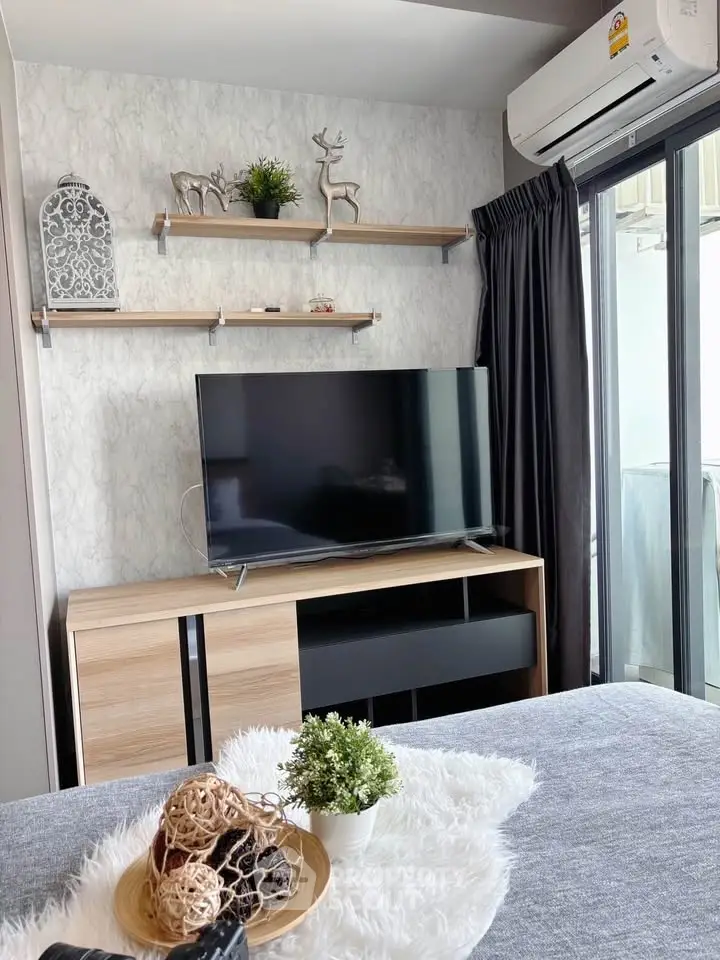 Modern living room with stylish decor and large TV, featuring sleek furniture and natural light.