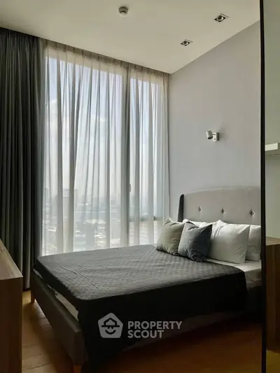 Modern bedroom with large window and stylish decor in a luxury apartment.