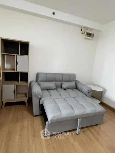Cozy living room with modern gray sofa and stylish shelving unit on wooden flooring.