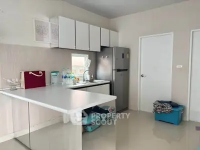 Modern kitchen with sleek cabinets and stainless steel fridge in a cozy apartment.