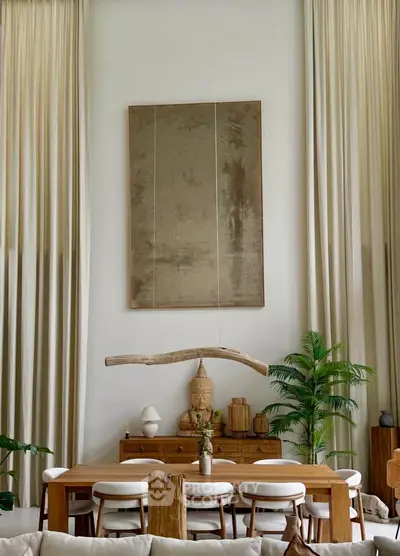 Elegant dining room with high ceilings, natural wood furniture, and lush greenery.