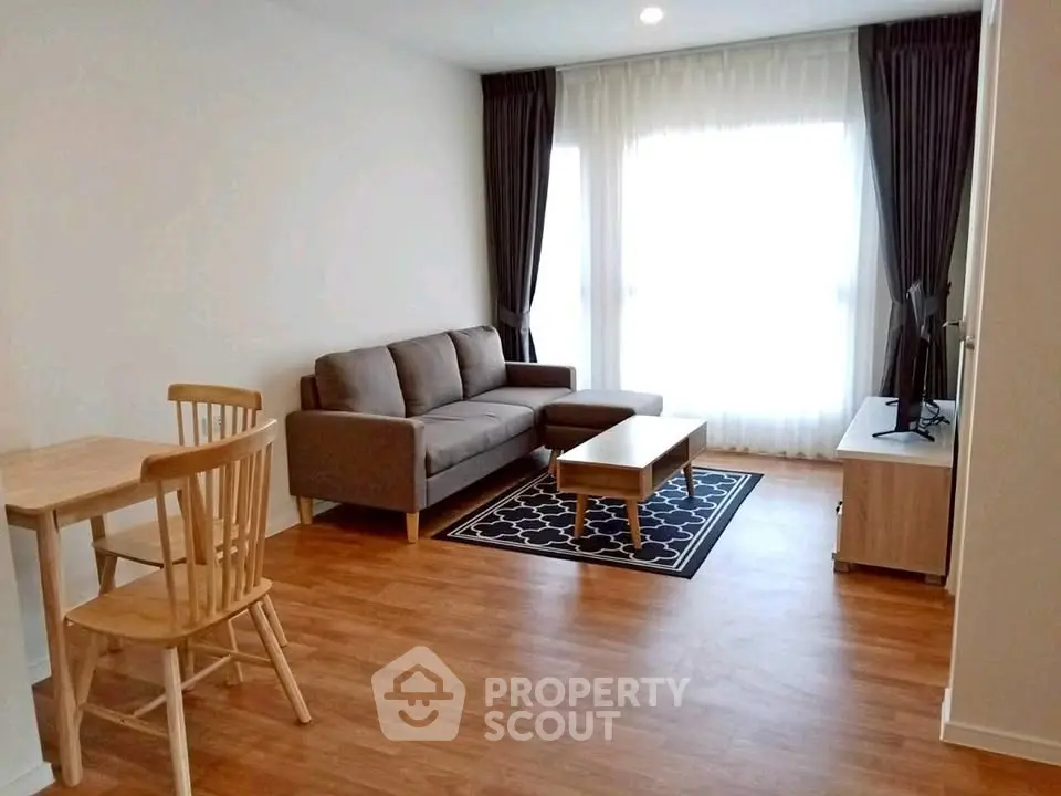Modern living room with cozy sofa, wooden flooring, and natural light from large windows.