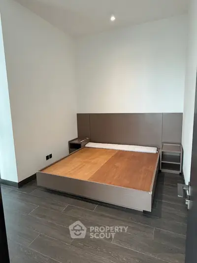 Modern minimalist bedroom with sleek wooden flooring and contemporary bed frame.