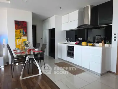 Modern kitchen with sleek white cabinets and dining area, featuring contemporary decor and stylish appliances.