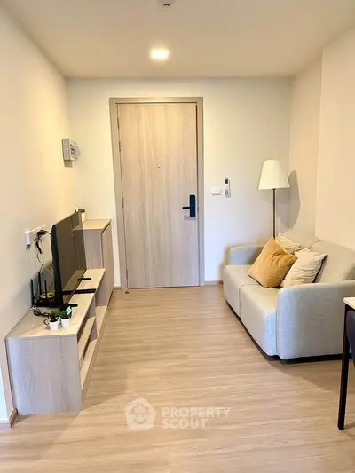 Cozy living room with modern decor and wooden flooring, featuring a comfortable sofa and sleek TV unit.