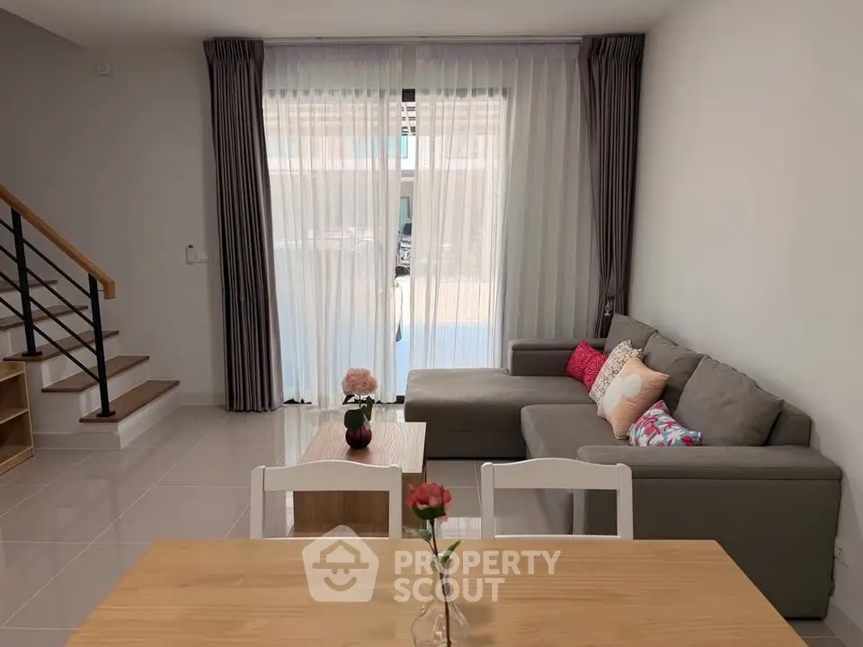 Modern living room with stylish sofa and elegant decor, featuring large windows and natural light.