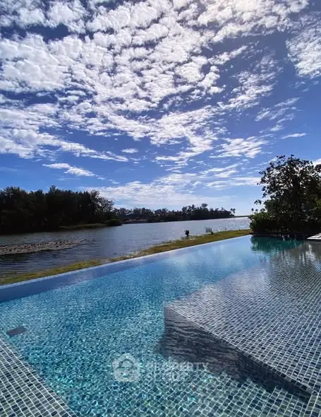 Stunning infinity pool with breathtaking waterfront view under a vibrant sky.