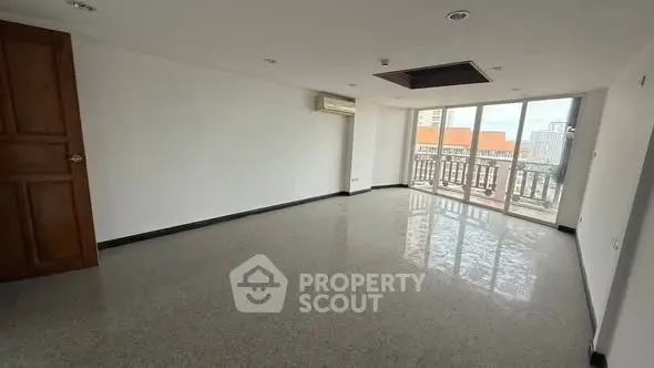 Spacious empty room with large windows and balcony view.