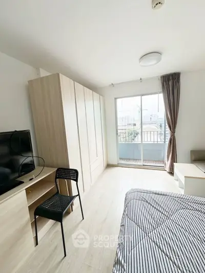 Bright modern bedroom with balcony view, featuring sleek furniture and ample natural light.