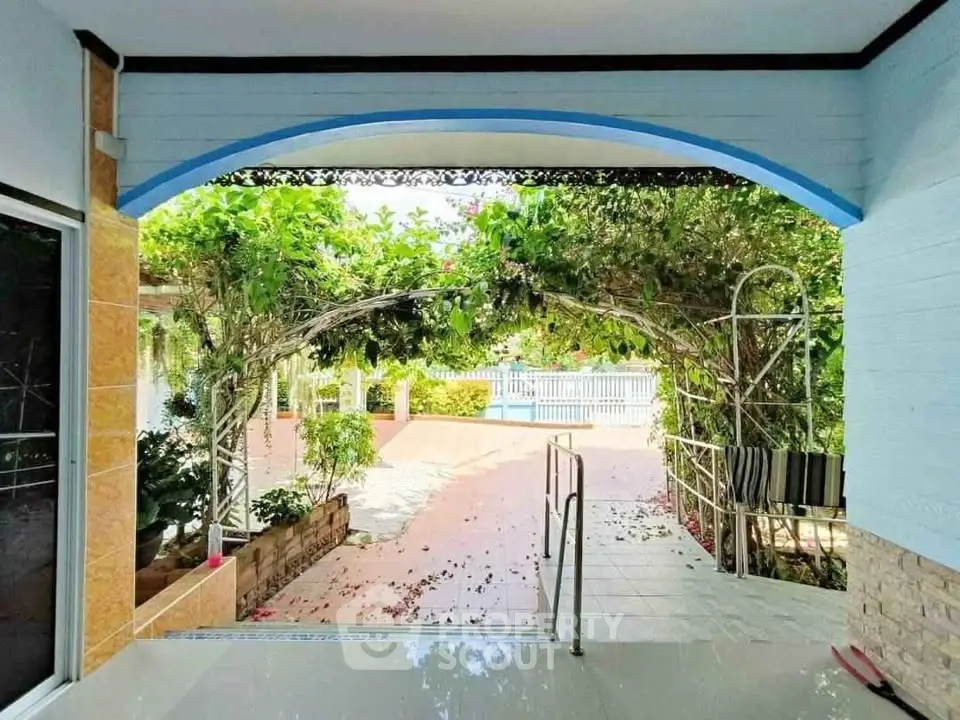 Charming garden view from a covered patio with lush greenery and pool access.
