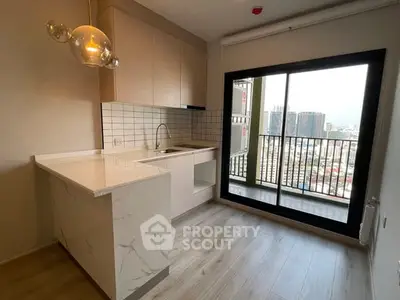 Modern kitchen with marble countertops and city view from balcony in high-rise apartment.