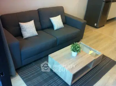 Modern living room with stylish gray sofa and wooden coffee table on a chic striped rug.