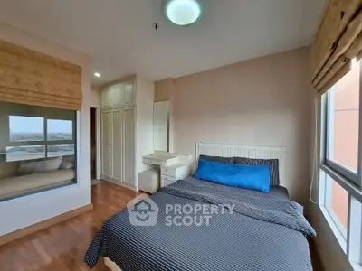 Cozy bedroom with large window and built-in wardrobe, perfect for relaxation.