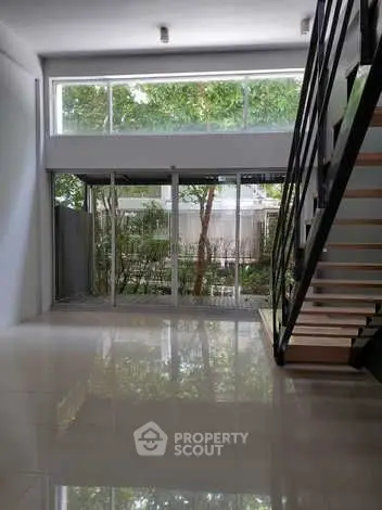 Spacious modern living room with large windows and sleek staircase