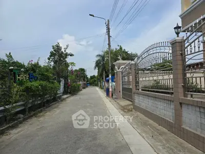 Charming residential street with gated entrance and lush greenery, perfect for serene living.