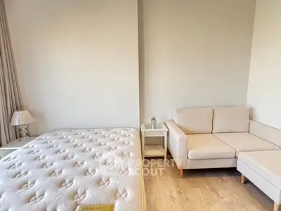 Cozy bedroom with plush mattress and stylish beige sofa, perfect for relaxation and comfort.