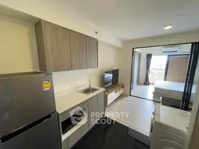 Modern apartment kitchen with sleek cabinetry and open layout leading to living area.