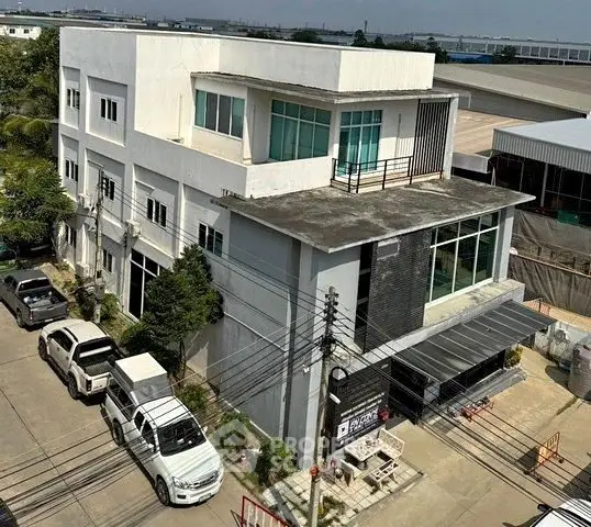 Modern commercial building with large windows and parking area in urban setting.