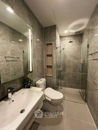 Modern bathroom with glass shower and sleek fixtures in luxury apartment
