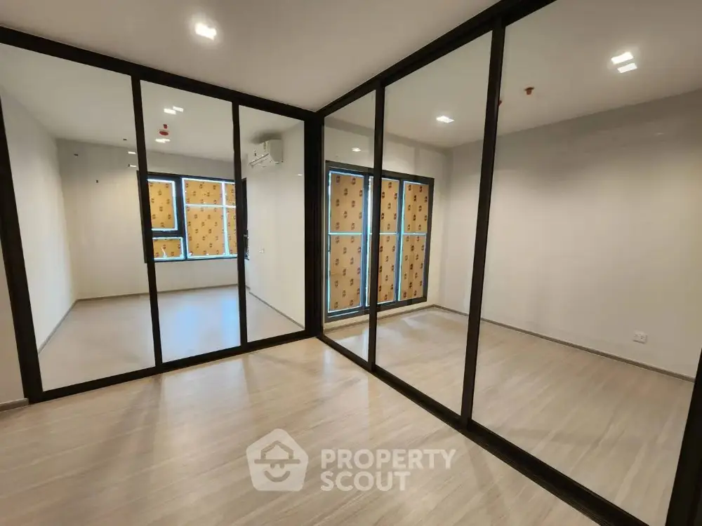 Spacious modern room with large mirrored sliding doors and wooden flooring