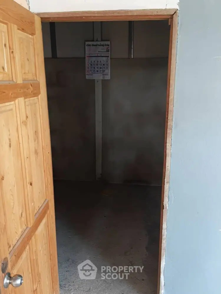 Simple interior room with wooden door and plain walls, ideal for storage or utility use.