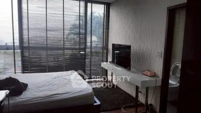 Modern bedroom with large windows and sleek furniture, perfect for urban living.