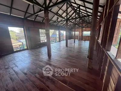 Spacious wooden interior with high ceilings and large windows, perfect for versatile use.