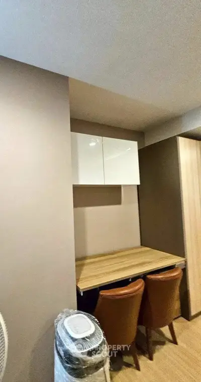 Modern study area with sleek wooden desk and chairs in a stylish apartment.