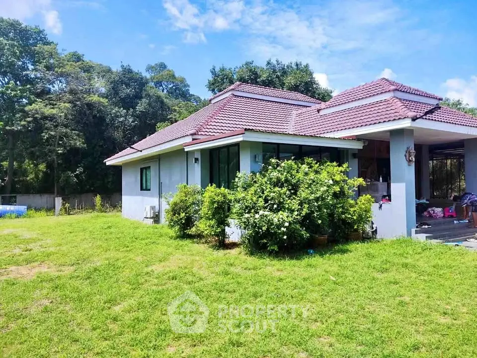Charming single-story house with red-tiled roof and lush green lawn, perfect for serene living.