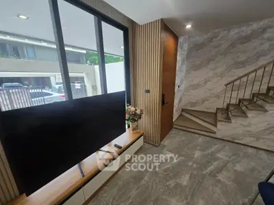 Modern living room with sleek TV setup and stylish staircase in contemporary home.