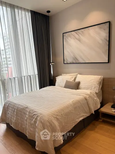 Modern bedroom with elegant decor and large window offering natural light.