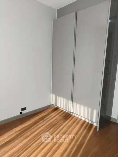 Minimalist bedroom with sleek built-in wardrobe and wooden flooring.