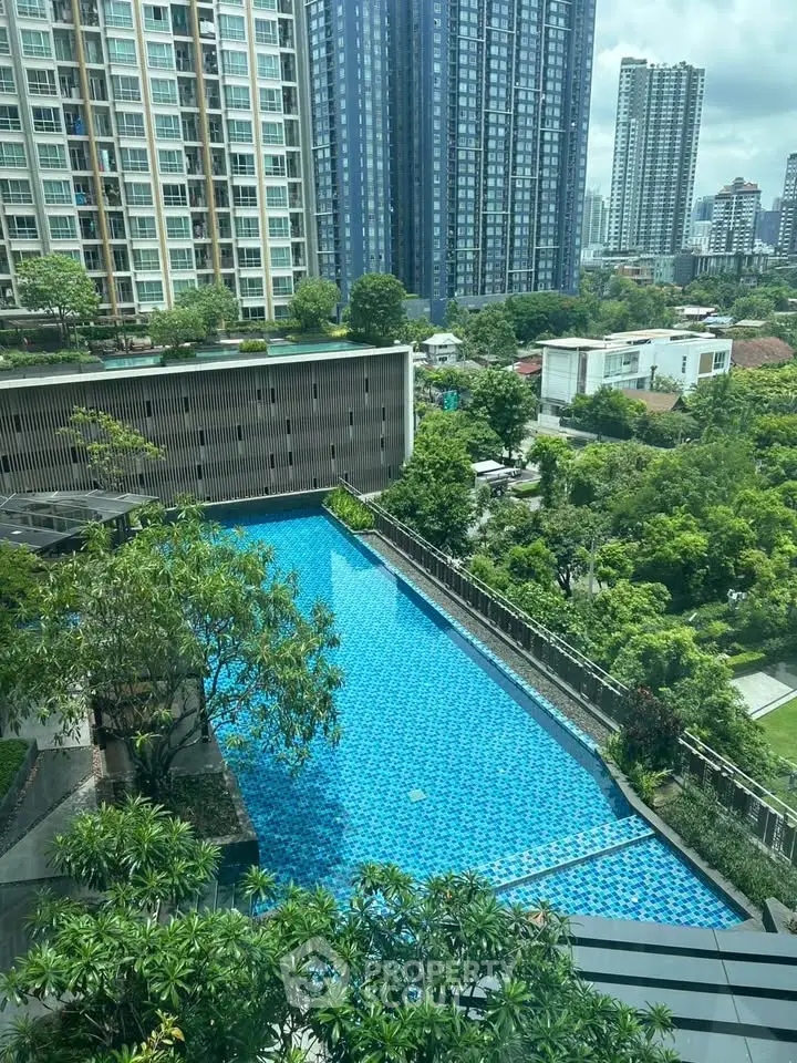 Stunning high-rise view with luxurious pool and lush greenery in urban setting.