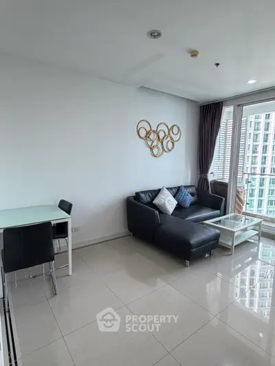 Modern living room with sleek black sofa and glass table, featuring a stylish wall decor and city view.